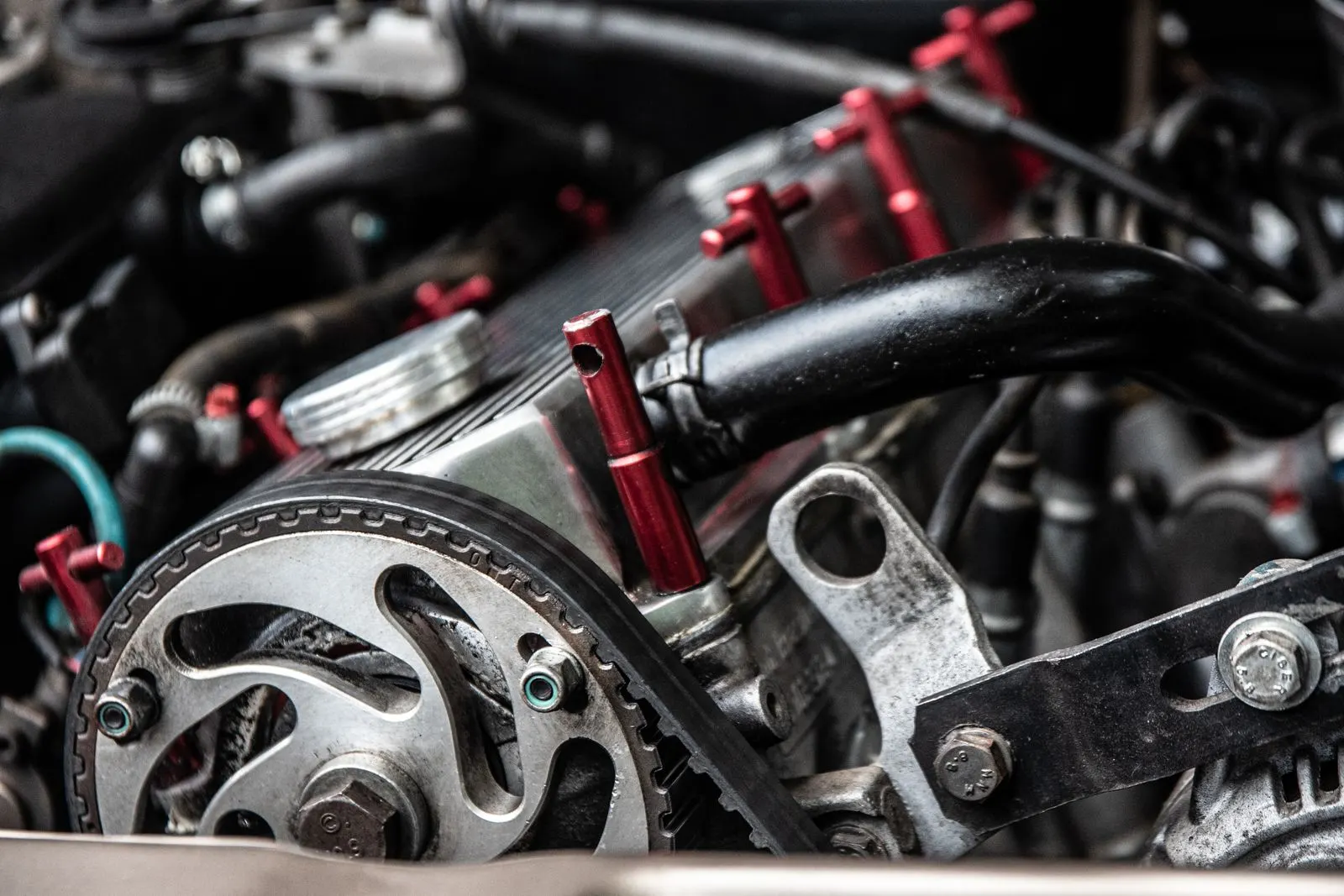 Close-up of a toothed timing belt wrapped around a camshaft sprocket at the front of a car engine