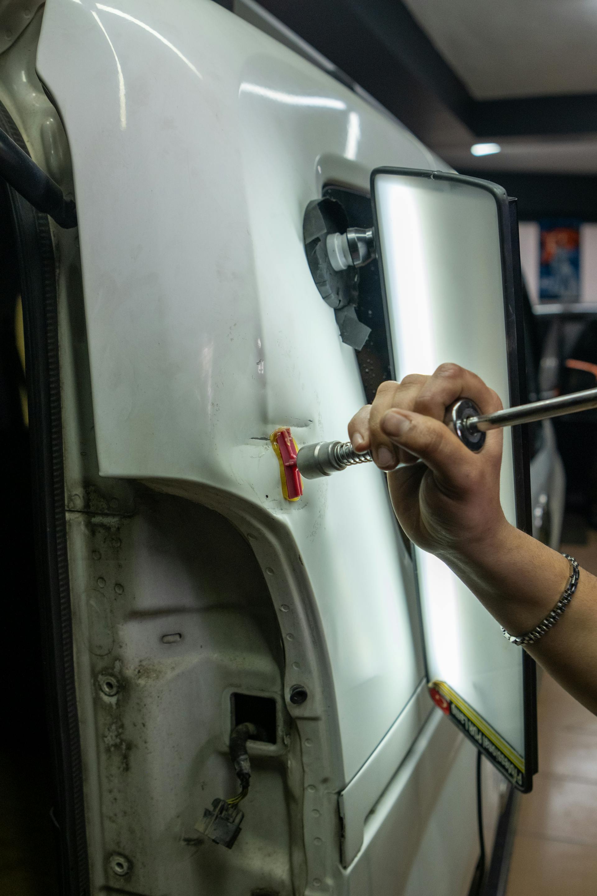 Close-up of vehicle dent repair using specialized tools
